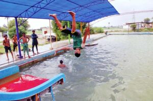 Youngsters jumping and swimming in swimming pool to get some relief from scorching hot weather in the city.
