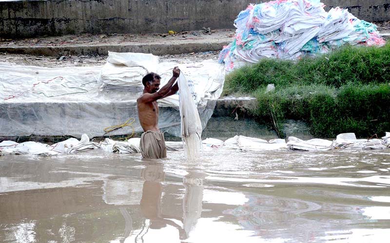 A man washing plastic sacks in local canal for resell
