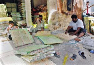 Workers are busy filling husk in frames of air coolers at their workplace.