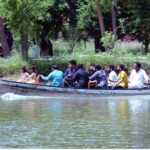 People are enjoying boat ride in water pond at local park during hot weather.