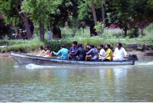 People are enjoying boat ride in water pond at local park during hot weather.