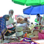 Women purchasing handmade fans from a roadside vendor due to a power outage during hot weather in the city