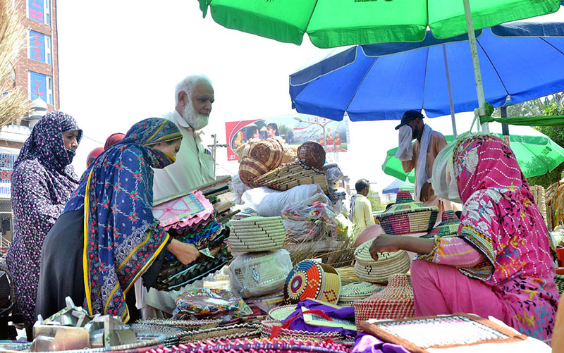 Women purchasing handmade fans from a roadside vendor due to a power outage during hot weather in the city