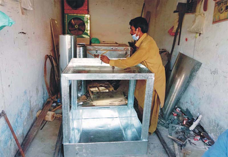 Worker busy preparing air cooler body from iron sheet at his workplace.