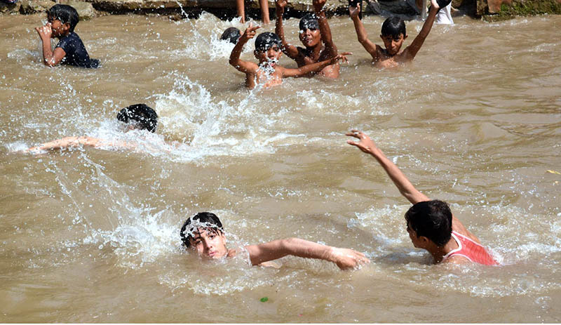 Youngsters enjoy bathing in pond to get some relief from hot weather in the Provincial Capital