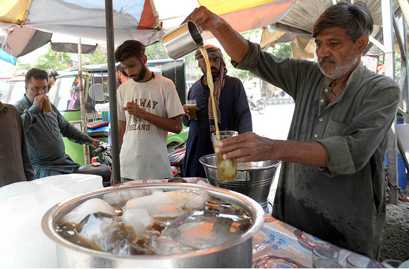 A vendor selling traditional summer drink (Shakar Cola) at his roadside setup.