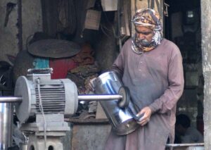 A worker polishing a stainless steel pot at his workplace.