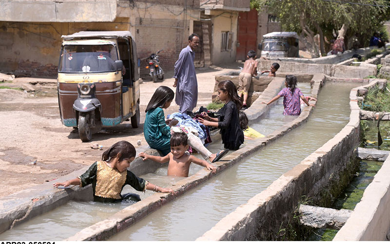 Children bathing in the channel of tub-well to get relief from scorching hot weather in the city