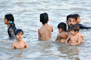 People enjoy bathing in the Indus River to get relief from hot weather in the city.