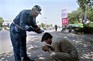 A traffic warden helping a citizen suffered from hot weather at Club Chowk during scorching hot weather in the city.