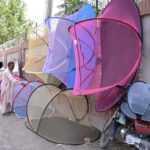 A vendor arranging and displaying mosquito nets at City Road to attract the customers
