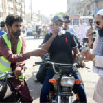Volunteers offer water to bikers, providing much-needed relief as temperatures soar in the city