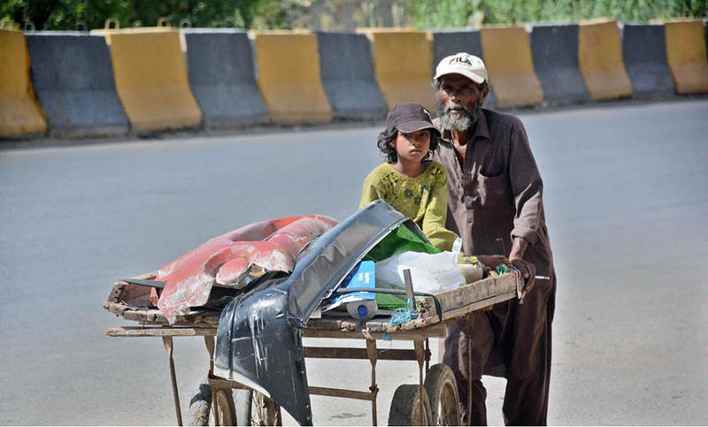 A street vendor pushes a hand cart loaded with scraps, carrying a child along the way, showcasing resilience and dedication to earn livelihood for family