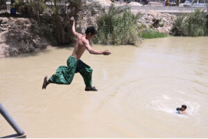 Youngster jumping and bathing in the canal to get relief from hot weather in the city.