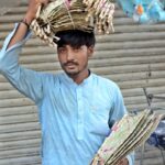 A vendor selling hand fans while shuttling on the road