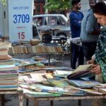 Woman selecting old books from a roadside stall at Mall Road