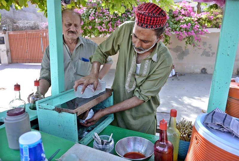 A vendor busy in crushing ice for making ice lolly on his cart at Shahenabad Road.