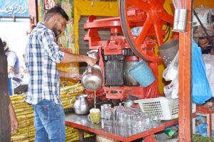 A vendor selling sugarcane juice to attract customers during hot day in the city.