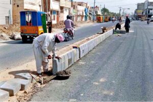 Labourers busy fixing cemented block at center of the road.