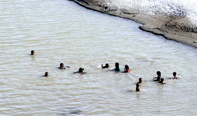 A large number of children bathing in Indus River to get relief from hot weather in the city.