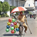A disabled man is selling balloons and Plastic footballs on bicycle struggling to earn a livelihood for family.