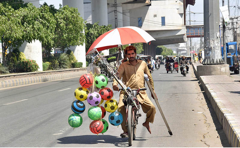 A disabled man is selling balloons and Plastic footballs on bicycle struggling to earn a livelihood for family.