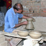 A craftsman busy in preparing clay-made pot at his workplace.