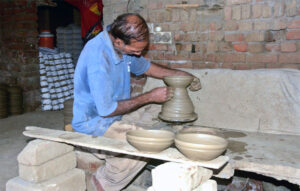 A craftsman busy in preparing clay-made pot at his workplace.