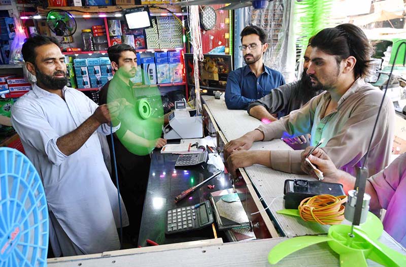 Customers selecting and purchasing 12 volt fan from a local vendor at Shoba Bazaar.