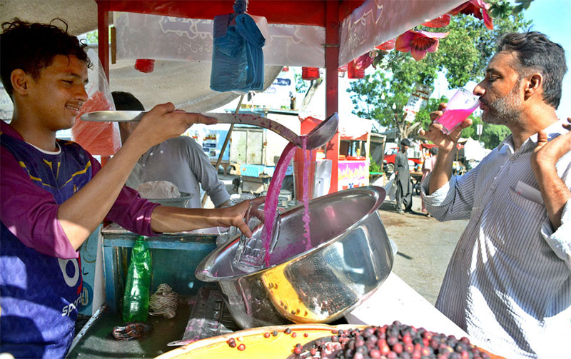 A man drinking falsa juice from a street vendor in hot, humid day.