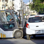 Traffic warden removing the wrong parked car with the help of a forklift in front of the excise office for the smooth flow of traffic at Mall Road