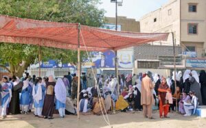 Students congregate outside the exam center and seeking shelter from the blistering sun beneath under the tent.