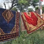 A vendor displayed carpets at his road side setup to attract the customers.