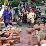 A woman buying clay pot from road side vendor.