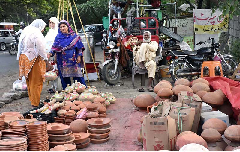 A woman buying clay pot from road side vendor.