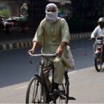 A cyclist covers his face with a scarf to avoid the hot and humid weather in the Provincial Capital.