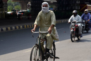 A cyclist covers his face with a scarf to avoid the hot and humid weather in the Provincial Capital.