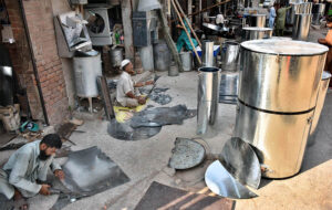 Workers busy in preparing huge iron containers for the storage of wheat to the customers at their workplace.