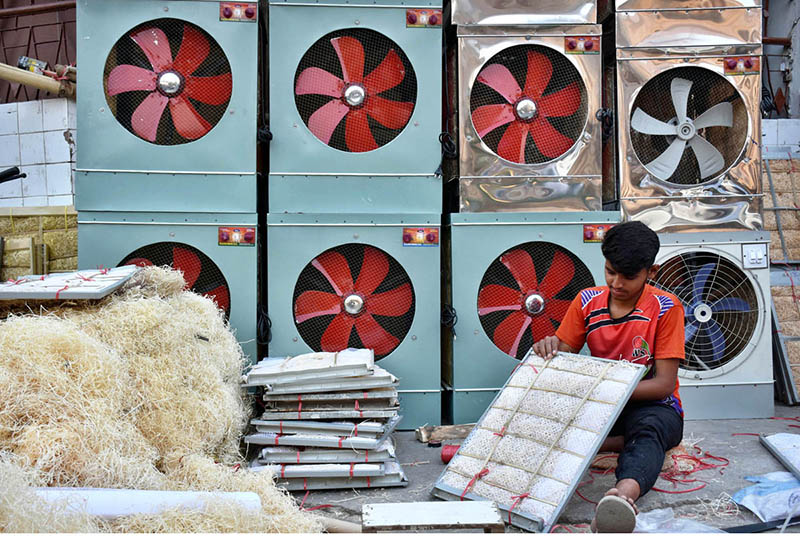 Young worker busy in preparing “Khas” for air-coolers at his roadside workplace.