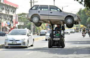 A traffic police warden is picking up the wrongly parked vehicle with the help of forklift at Mall road.