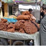 Man buying dried Plums from vendor at Meezan Chowk as per increased demands in hot weather in the city.