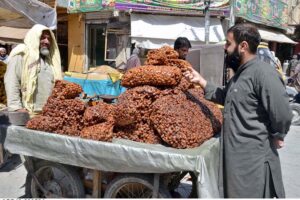 Man buying dried Plums from vendor at Meezan Chowk as per increased demands in hot weather in the city.