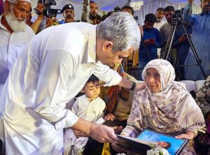 Federal Minister for Interior Mohsin Naqvi presenting allotment letter of home to the mother of a martyr.