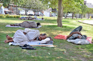 Labourers enjoying nap under the shade of trees in a local park during hot weather in Provincial Capital.