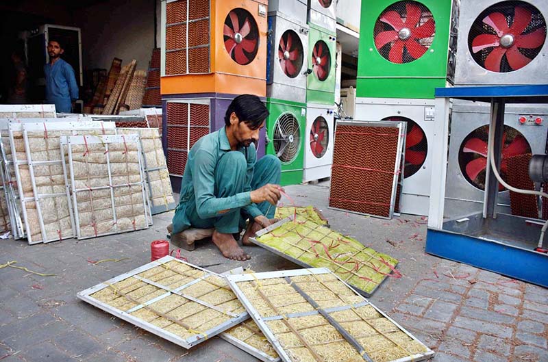 A worker preparing “Khas” used in local made air-coolers at his roadside workplace.