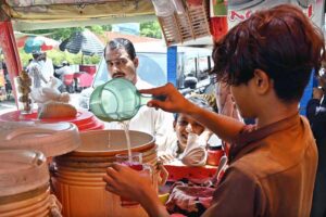 A vendor busy in preparing traditional summer drinks for customers at his roadside setup during extreme hot weather in the city.