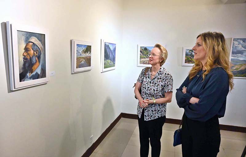 Visitors viewing paintings during exhibition 