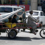 A Gypsy family makes their way on a tri-motorcycle braving the city's heat
