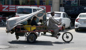 A Gypsy family makes their way on a tri-motorcycle braving the city's heat