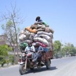 A person sitting on luggage loaded on tricycle loader rickshaw on the way at Chungi No.9